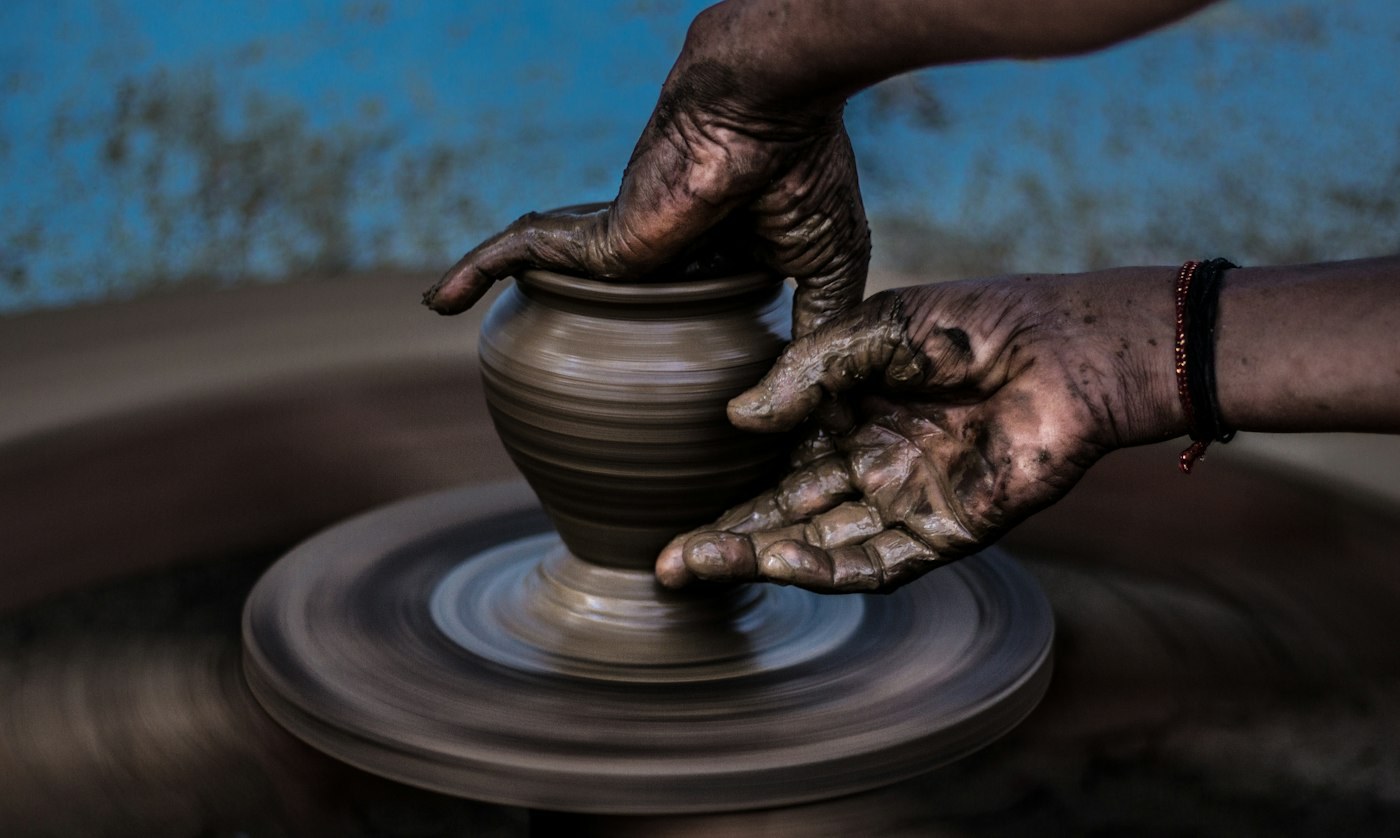 Hands shaping a clay pot on a wheel